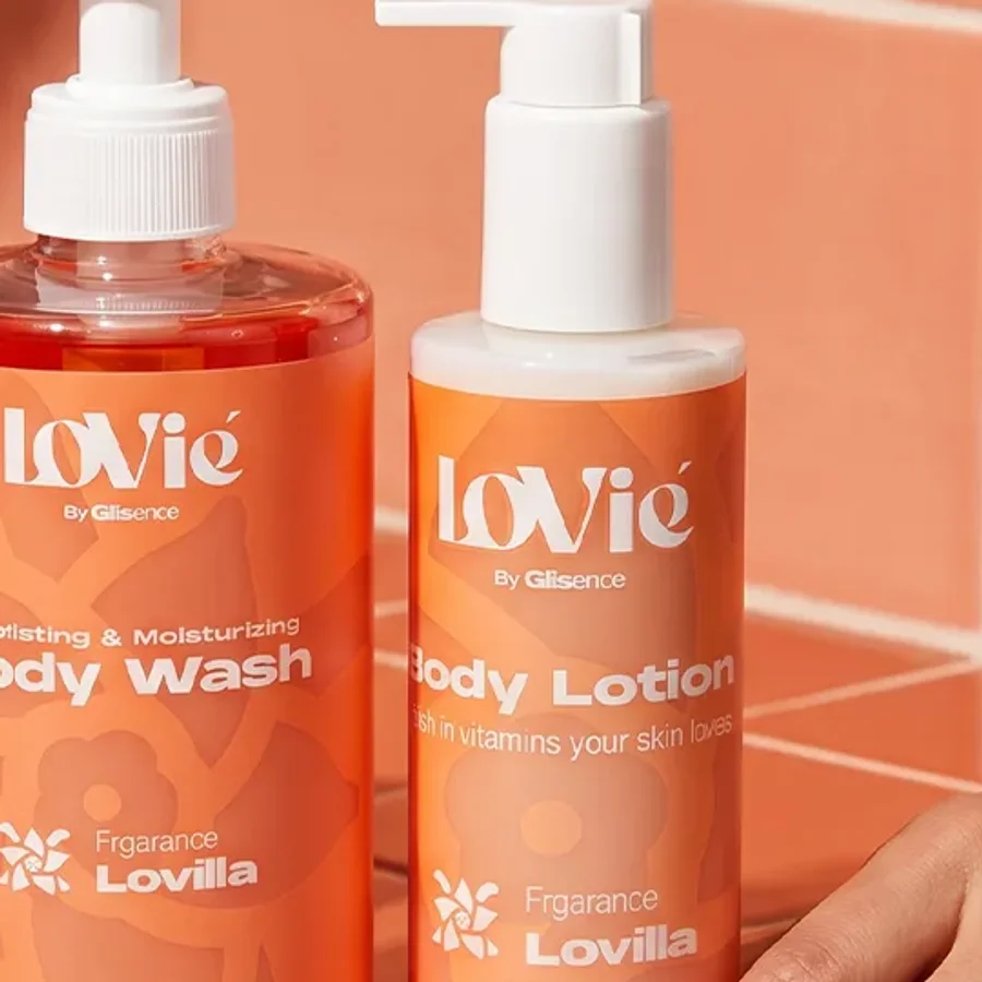 Close crop of the Lovie wordmark on the orange wash and lotion bottles in a campaign photograph.