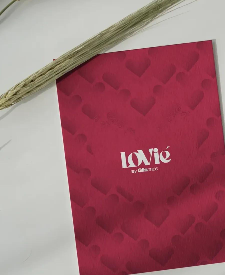 Close crop of the printed crimson Lovie card, the wordmark reversed in white over the heart motif.