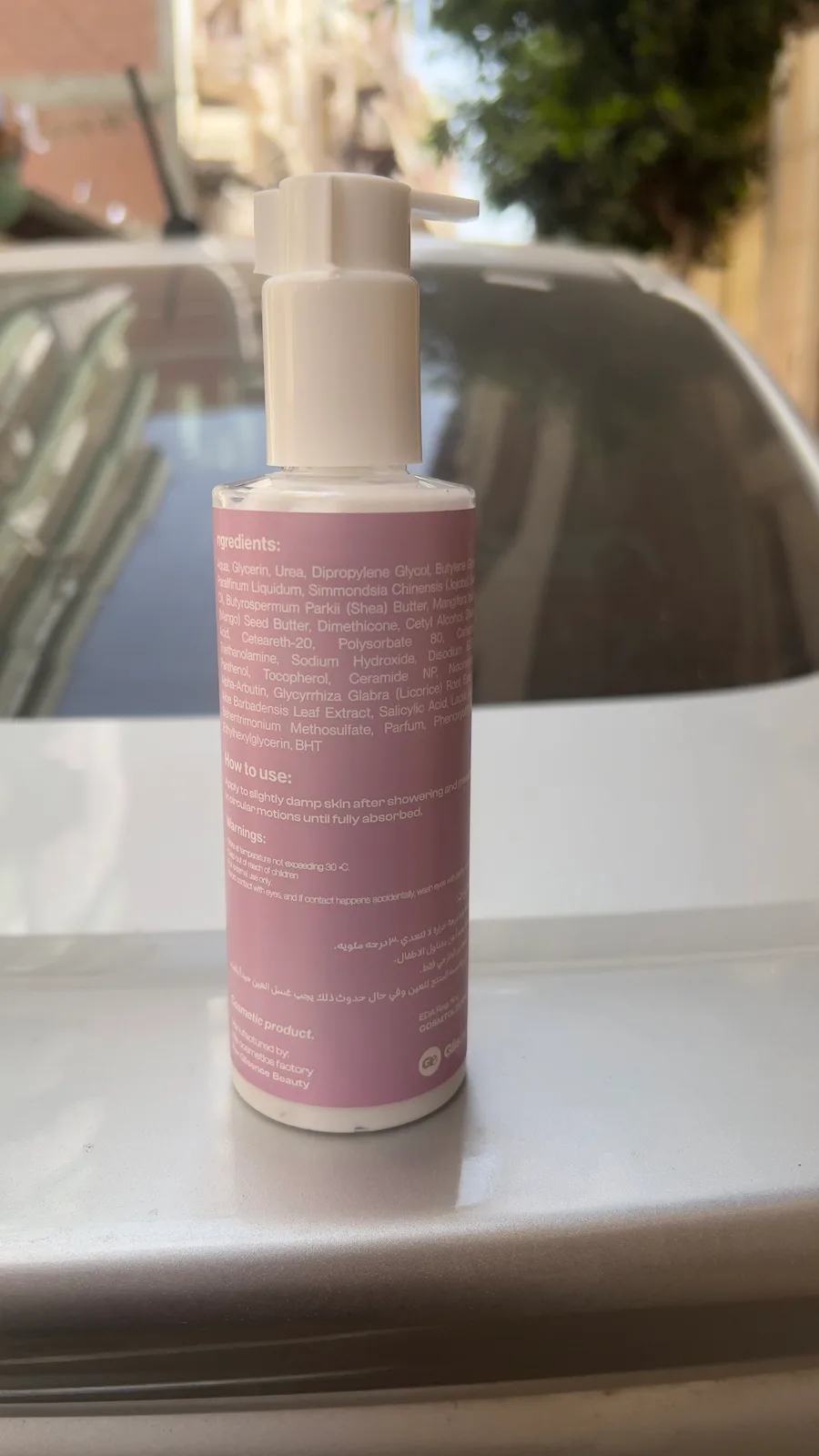 A printed Lovie body lotion bottle, ingredients side out, standing on a white car in a Cairo street.
