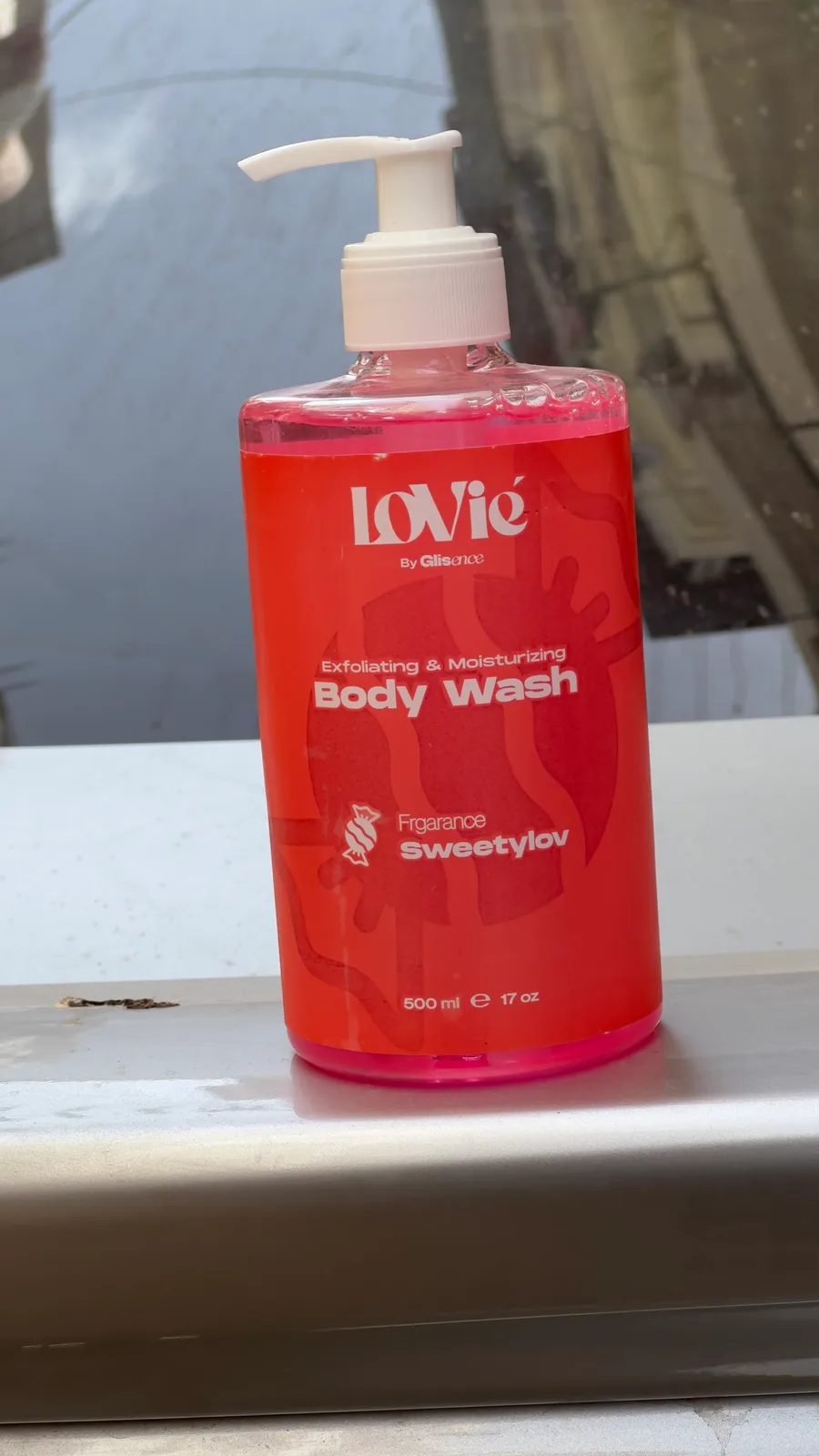 A printed red Sweetylov body wash standing on a car roof in a Cairo street, its front label facing the camera.