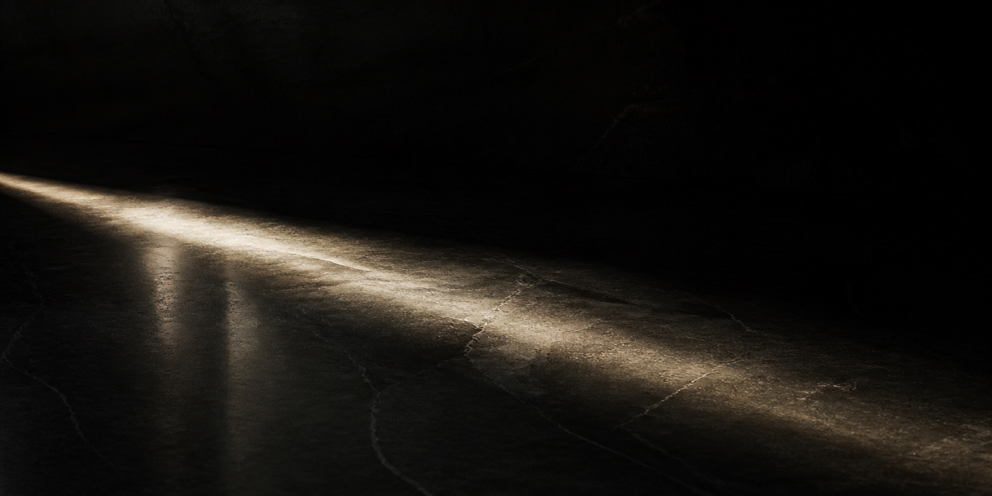 Single beam of light travelling across dark polished stone.