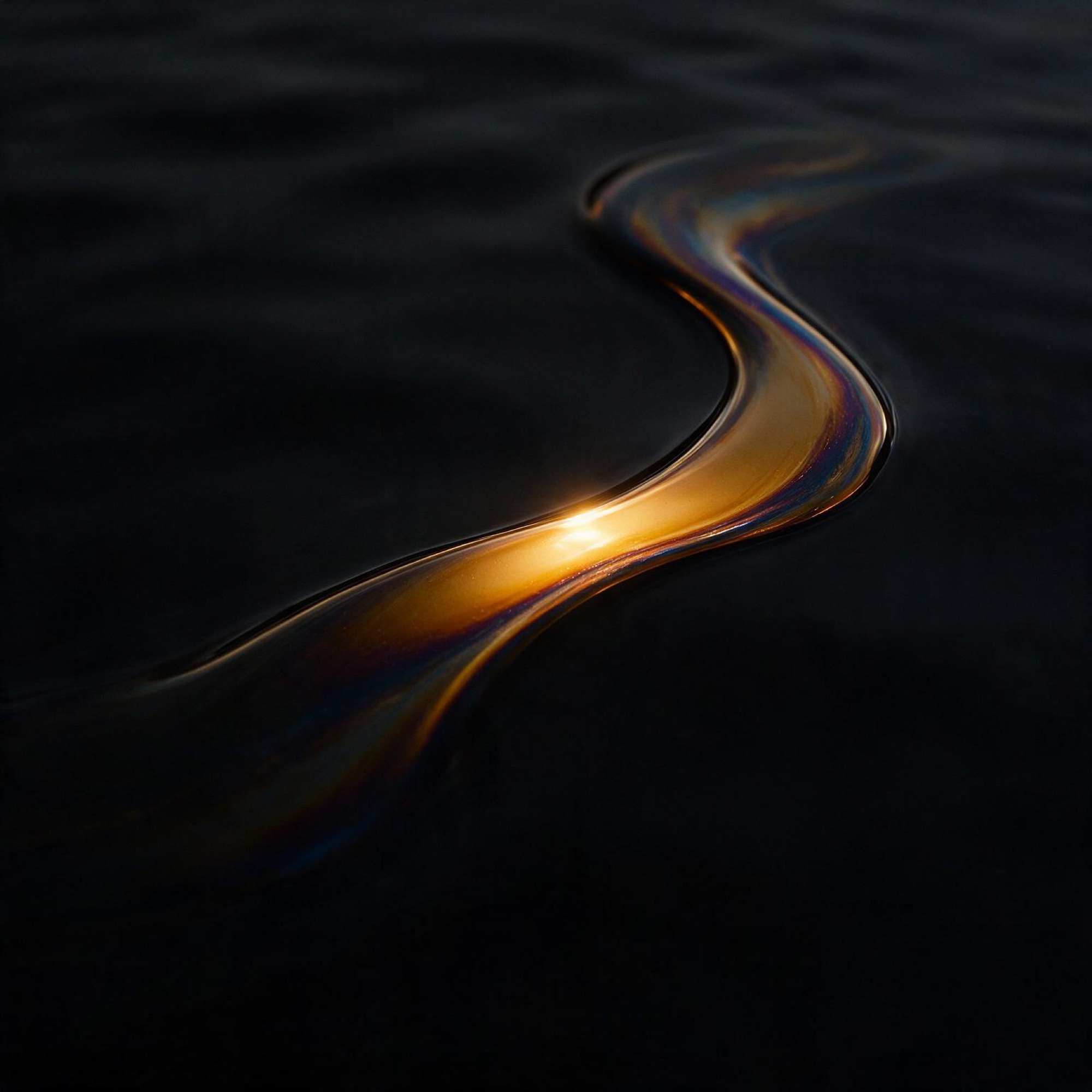 Abstract curve of oil meeting water with a single highlight in darkness.