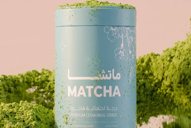 OMatcha campaign frame: a matcha tin dusted with green powder against a pastel ground, Arabic wordmark on the tin.